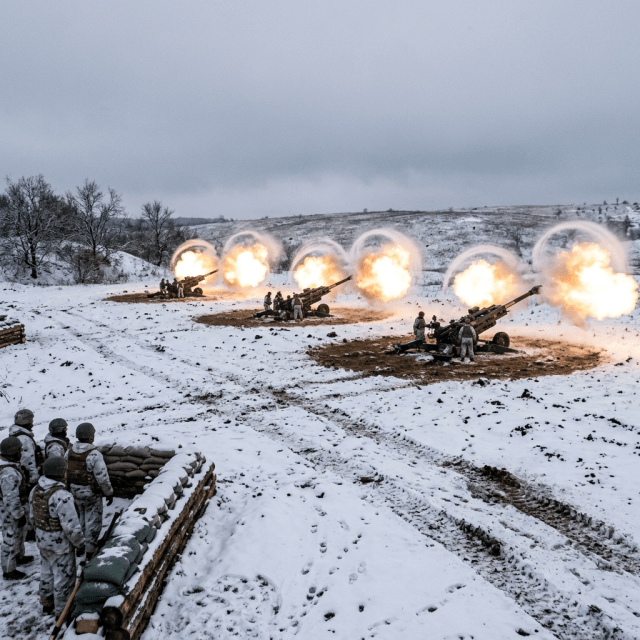 Artillery cannons firing with soldiers in snowy landscape