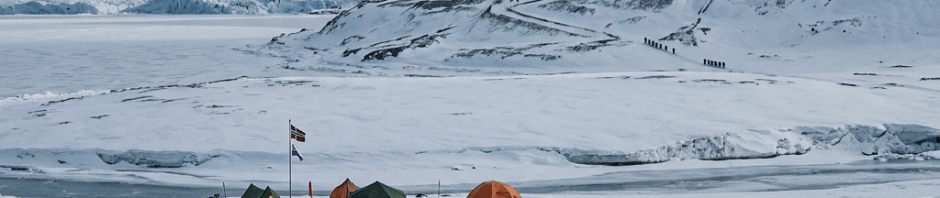 Expedition team and tents on snowy glacier beneath mountains