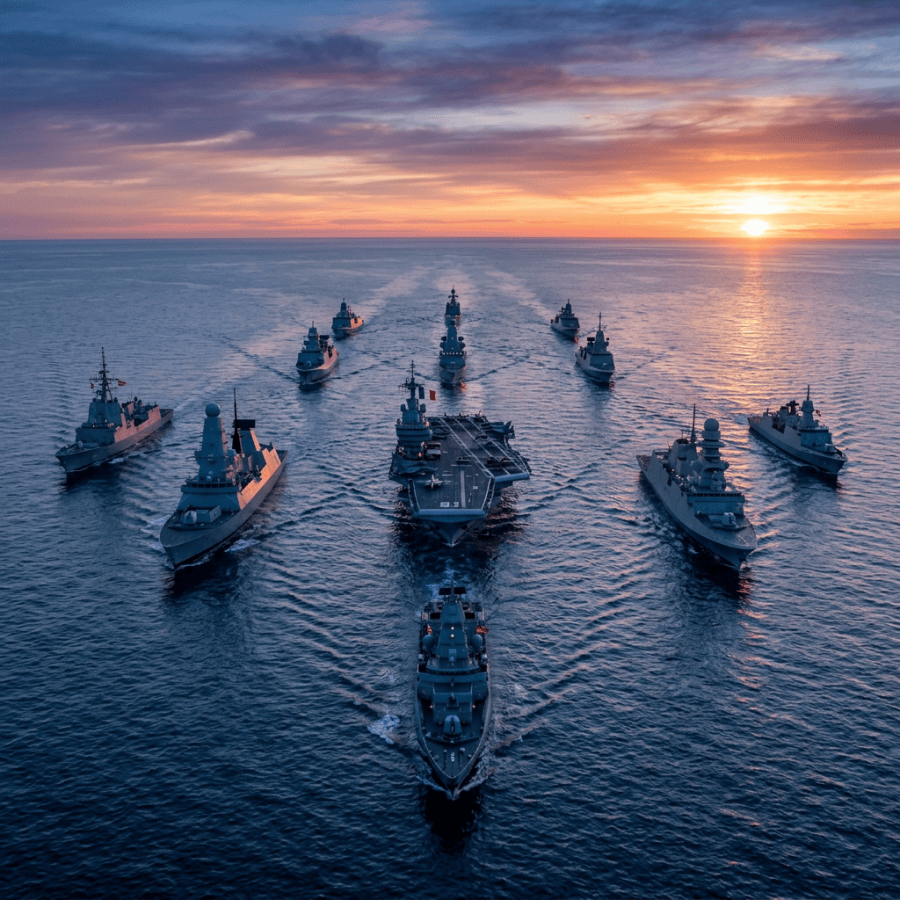 Naval fleet ships sailing in formation across the ocean at sunset