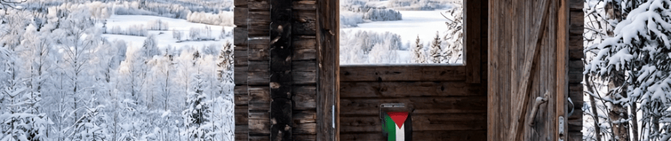 Open wooden shelter beside a snowy trail overlooking forested hills
