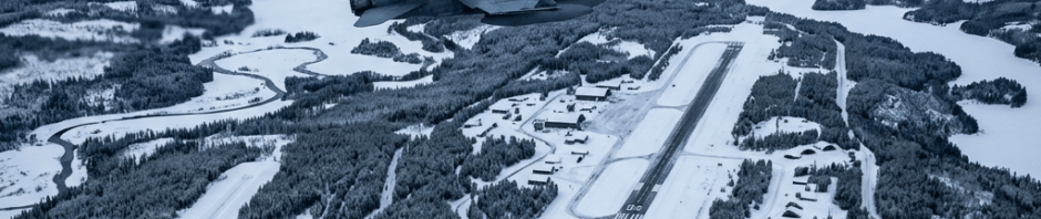 Three fighter jets flying over a snowy airbase and frozen lakes