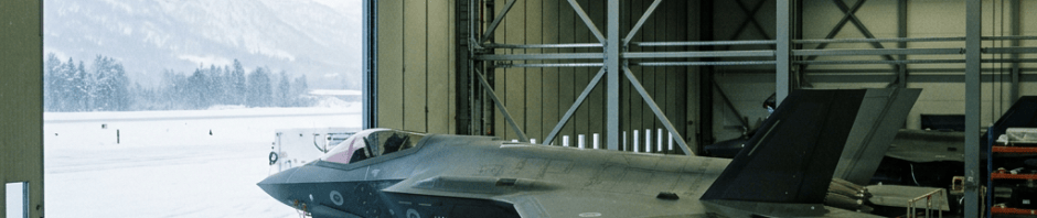 Modern fighter jet inside a maintenance hangar beside a snowy airfield